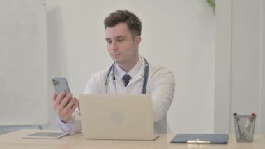 Genç Doktor Laptop kullanırken Smartphone kullanıyor