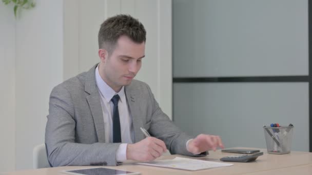 文書の作成 およびドルの計算に従事する若いビジネスマン — ストック動画