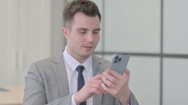 Portrait of Young Businessman Celebrating Win on Smartphone