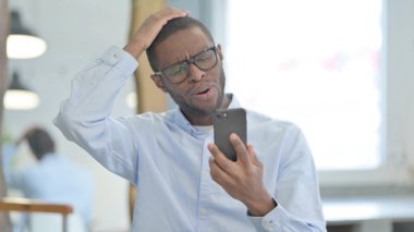 Portrait of African American Man with Loss on Smartphone
