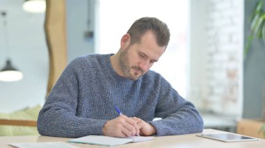 Mature Adult Man Writing while Sitting in Office