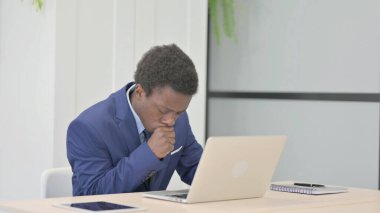 African Businessman Coughing while Working on Laptop