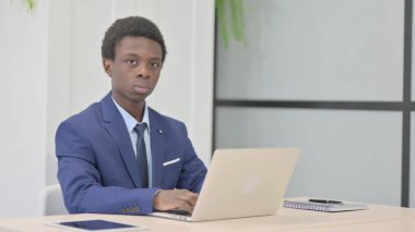 Dizüstü bilgisayar kullanırken kameraya bakan Afrikalı İşadamı