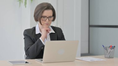 Old Senior Businesswoman Thinking while Working on Laptop