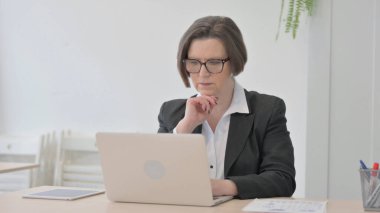 Old Senior Businesswoman Thinking while Working on Laptop
