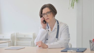 Old Senior Doctor Talking on Phone in Clinic