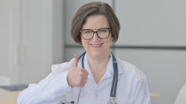 Yaşlı kadın doktorun portresi Başparmaklarını kaldırıyor.