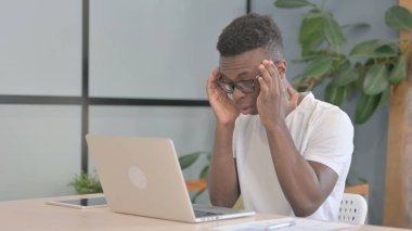 Baş ağrısı olan genç Afrikalı Laptop üzerinde çalışıyor