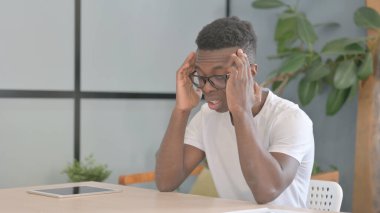 Young African Man with Headache in Office