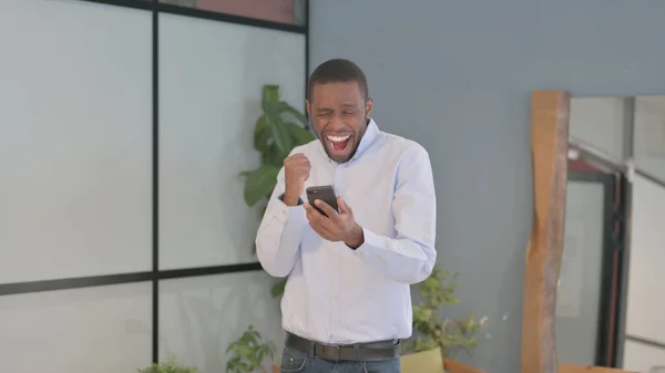 Excited African American Man Celebrating Win on Smartphone