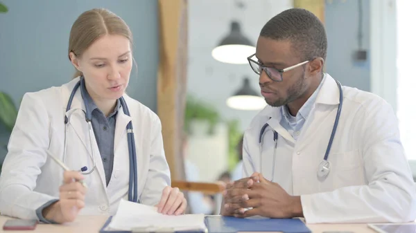 African American Doctor and Female Doctor Checking Patient Medical Report