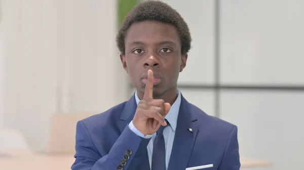 Young African Businessman with Finger on Lips, Asking for Silence