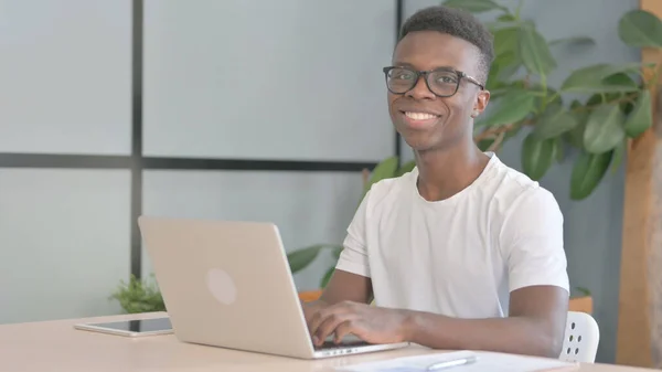 Ung Afrikansk Man Ler Mot Kameran När Använder Laptop — Stockfoto