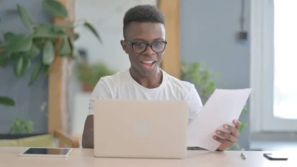 African Man Celebrating Success while Reading Documents in Office