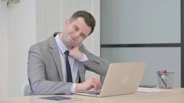 Young Businessman with Neck Pain Working on Laptop