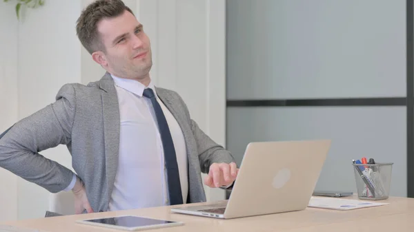 Young Businessman with Back Pain Working on Laptop