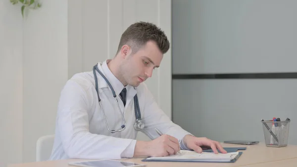 Young Doctor Working on Medical report in Clinic, Paperwork