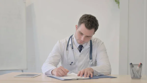 Young Doctor Working on Medical report in Clinic, Paperwork