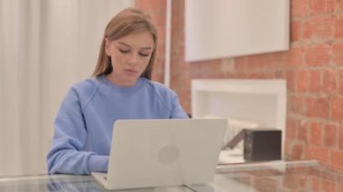 Dizüstü bilgisayarda çalışan bilek ağrısı olan genç bir kadın.