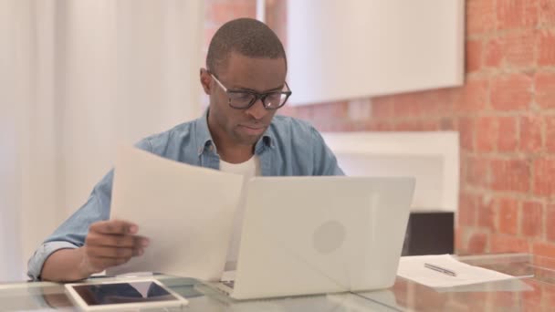 ラップトップと文書の損失によってショックを受けたアフリカ人男性 書類仕事 — ストック動画