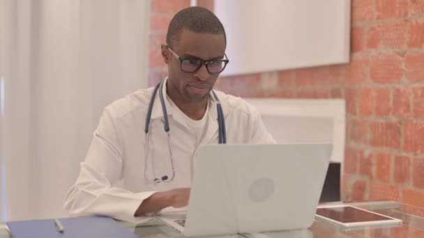 Joven Médico Africano Sonriendo Cámara Mientras Trabaja Ordenador Portátil — Vídeos de Stock