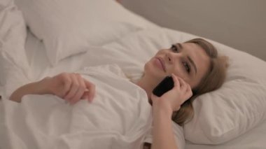 genç kadın yatakta telefonda konuşuyor