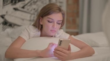 Genç Kadın, Midenin Üzerinde Yatarken Akıllı Telefon Kullanıyor