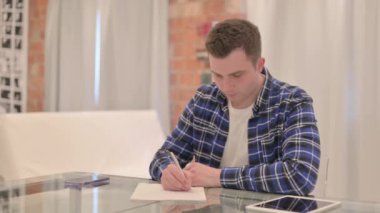 Evraklar üzerinde çalışan, evrak işlerini yapan sıradan bir genç.