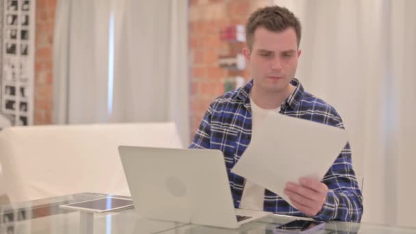 Junger Mann Feiert Erfolg Mit Laptop Und Dokumenten Papierkram — Stockvideo