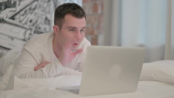 Mladý Muž Dělá Video Chat Notebooku Zatímco Leží Břiše Posteli — Stock video