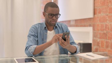 İş yerinde akıllı telefon kullanan Afrikalı adam