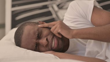 Yatakta yatan baş ağrısı olan Afrikalı adamın yan görüntüsü