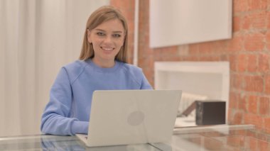 Young Woman Shaking Head in Approval while Working on Laptop