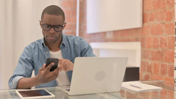 Hombre Africano Que Trabaja Ordenador Portátil Uso Smartphone —  Fotos de Stock