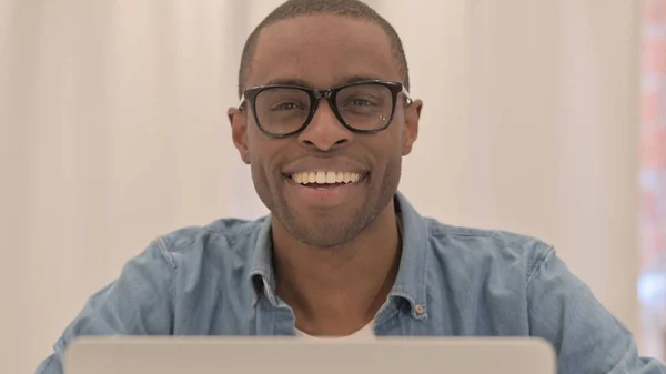 Afrikansk Man Ler Mot Kameran När Arbetar Laptop — Stockfoto