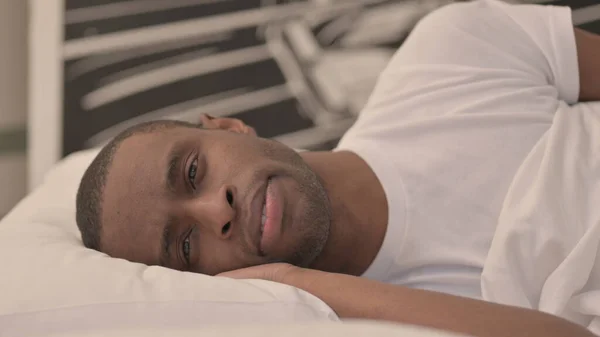 ベッドで寝そべっている深刻なアフリカ人男性の側面図 — ストック写真