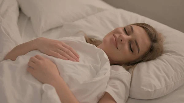 寝るためにベッドに寝そべっている疲れた若い女性 — ストック写真