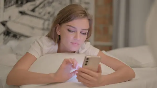 Jonge Vrouw Met Behulp Van Smartphone Tijdens Het Liggen Bed — Stockfoto