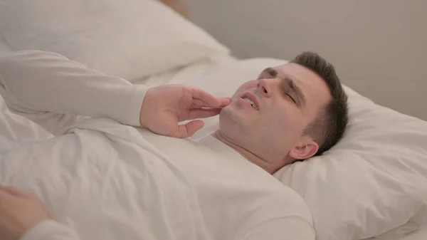 ベッドに横たわっ歯痛を持つ若い男 — ストック写真