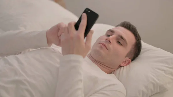 Fiatal Férfi Használ Okostelefon Miközben Fekszik Ágyban — Stock Fotó