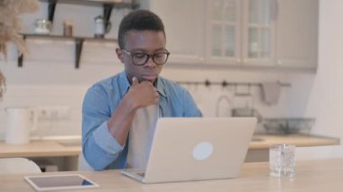 Genç Afrikalı Adam laptopta düşünüyor ve çalışıyor.