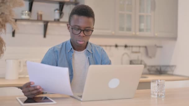 阅读非洲青年男子的文件和关于笔记本电脑的工作 — 图库视频影像