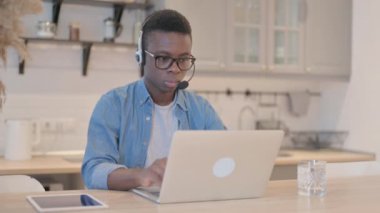 Kulaklıklı genç Afrikalı Çağrı Merkezindeki Kameraya doğru bakıyor