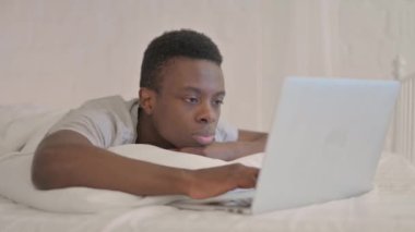 Genç Afrikalı Laptop 'ta çalışırken Yatakta Mide Uzanırken