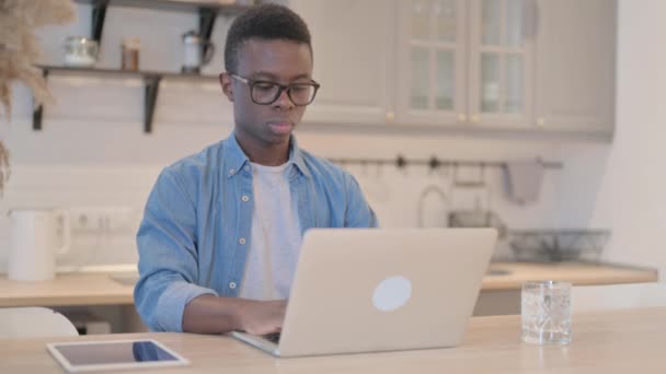 若いアフリカ人男性がノートパソコンで作業中に指を指す — ストック動画