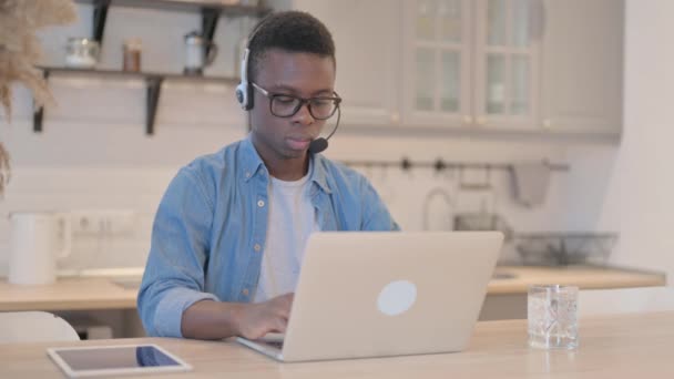 Ung Afrikansk Mann Med Hodetelefoner Som Arbeider Laptop – stockvideo