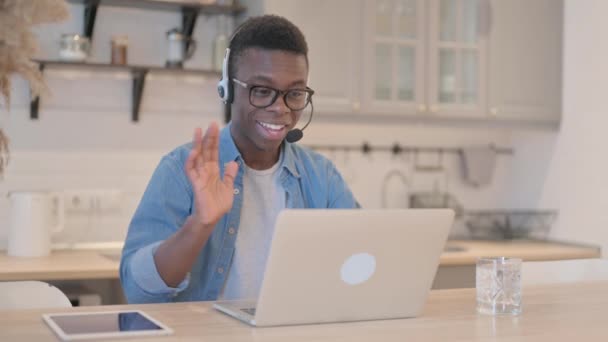 コールセンターでオンラインで顧客と話すヘッドセットを持つ若いアフリカ人男性 — ストック動画