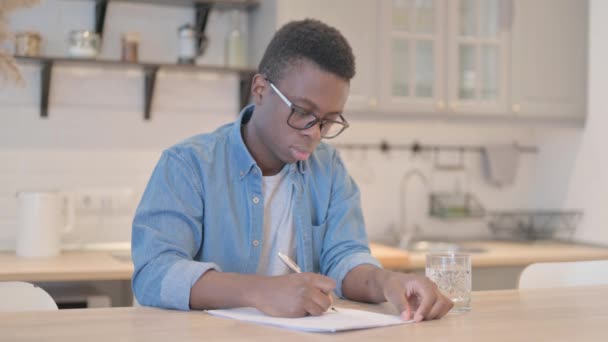 紙仕事をしながら書く若いアフリカ人男性 — ストック動画