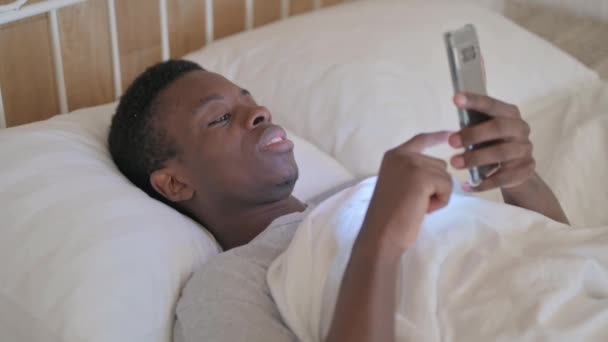 Homem Africano Jovem Usando Telefone Enquanto Deitado Cama — Vídeo de Stock