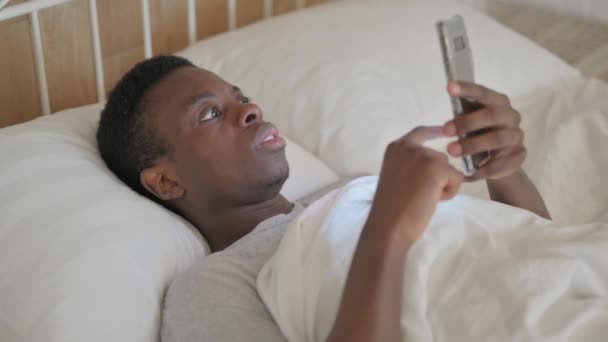 躺在床上的非洲年轻人因电话损失而震惊 — 图库视频影像